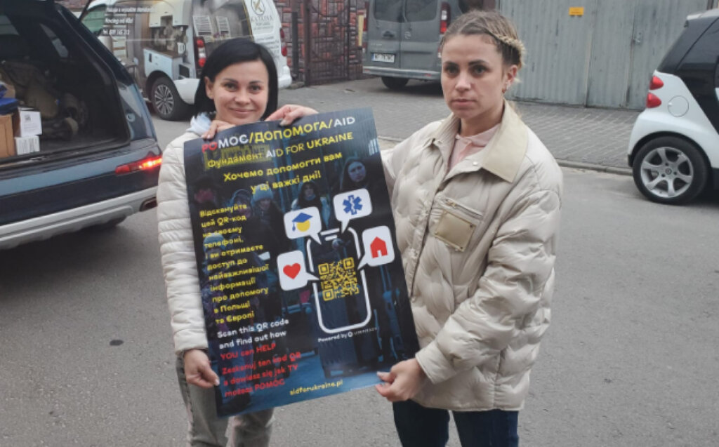 Ukrainian refugees holding the poster with instructions on accessing the Aid for Ukraine chatbot